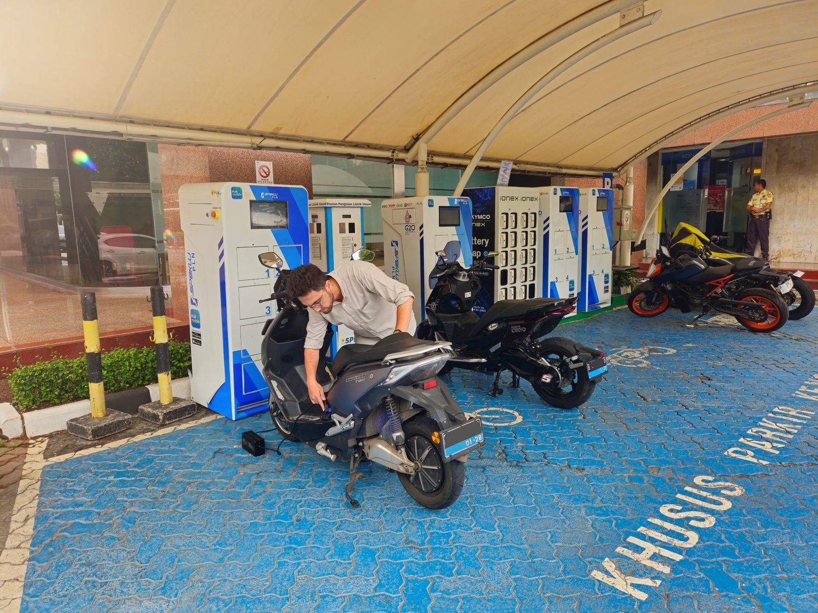 Pemilik motor listrik tengah melakukan pengisian daya baterai motor listriknya di Stasiun Pengisian Listrik Umum (SPLU) yang berada di dalam kawasan PLN Unit Induk Distribusi Jakarta Raya, Gambir, Jakarta Pusat. ( Foto : Istimewa )